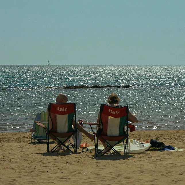 Due persone sulle sedie da spiaggia davanti al mare